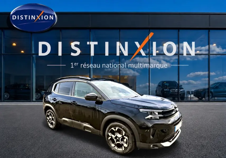 Citroën C5 Aircross noir vue 3/4 avant droit avec jantes alu et barres de toit devant vitrine Distinxion.