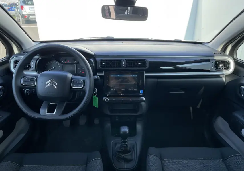 Vue frontale de l'intérieur noir de la Citroën C3 2024 avec tableau de bord moderne et écran tactile central.