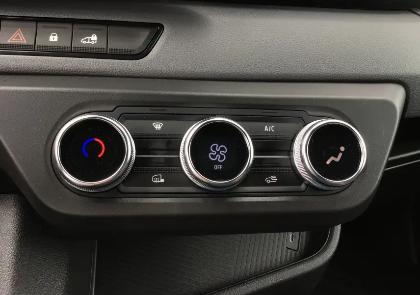 Vue rapprochée des commandes de climatisation du tableau de bord du Renault Master blanc 2025, avec réglages circulaires et affichage digital.