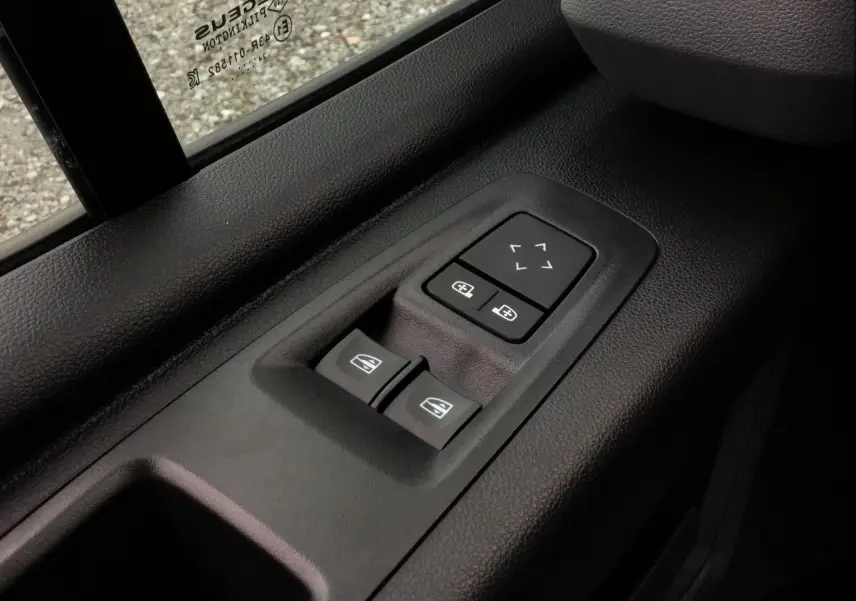 Gros plan sur les commandes de réglage des vitres et des rétroviseurs côté conducteur du Renault Master blanc 2025.