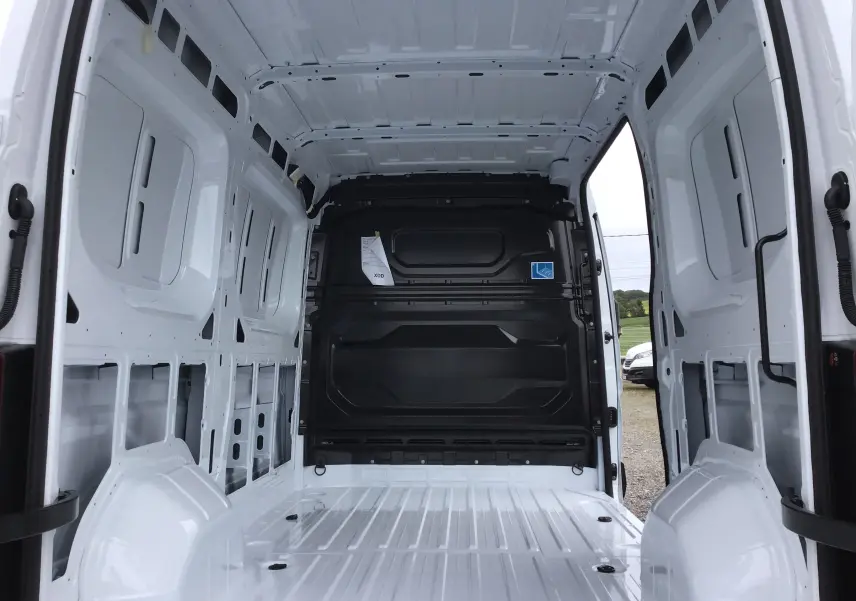 Intérieur vide du Renault Master blanc vu de l'arrière, montrant la cloison noire et la structure métallique du fourgon.