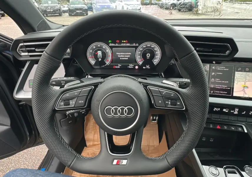 Vue intérieure centrée sur le volant cuir méplat S-Line et le tableau de bord numérique de l'Audi A3 2025.