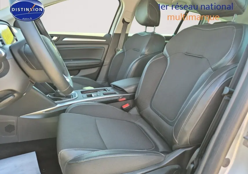 Vue intérieure côté conducteur de la Renault Mégane Break 2024, sièges tissu gris foncé avec surpiqûres blanches.