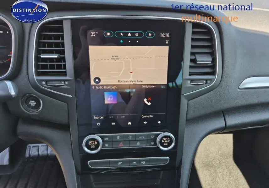Vue intérieure centrée sur l'écran tactile et la console centrale d'une Renault Mégane Break gris titanium 2024.