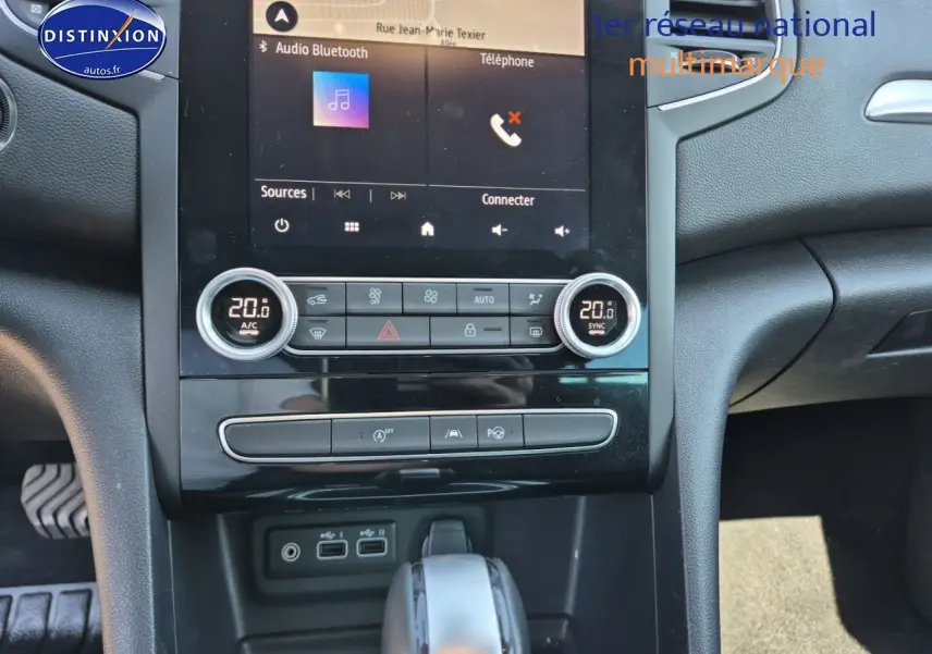 Vue rapprochée de la console centrale et levier de vitesse de la Renault Mégane Break gris Titanium, avec écran tactile et commandes clim.