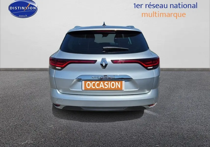 Vue arrière d'une Renault Mégane Break 2024 gris titanium avec feux arrière LED et barres de toit visibles.