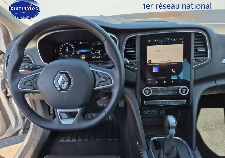 Vue intérieure avant centrée sur le volant multifonction et l'écran tactile du tableau de bord de la Renault Mégane Break 2024.