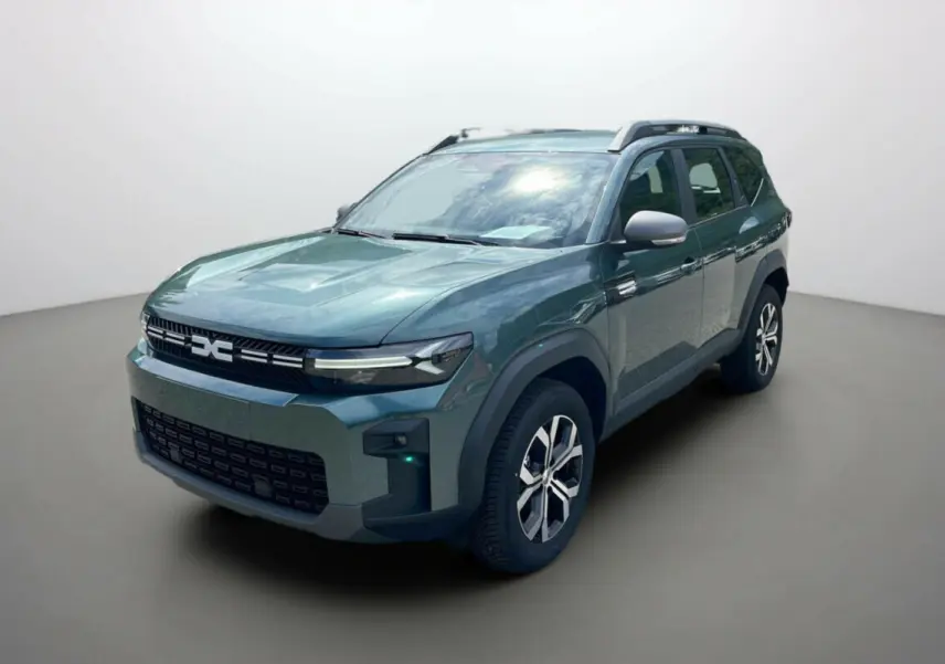SUV DACIA BIGSTER vert cèdre vu en 3/4 avant droit, avec calandre moderne et barres de toit visibles.