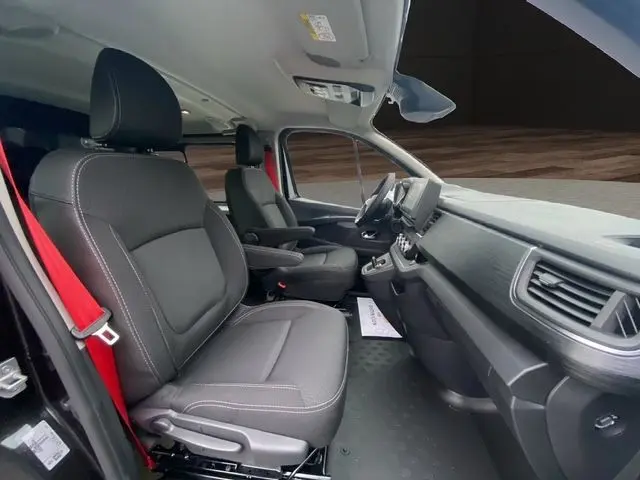 Vue intérieure côté conducteur du Renault Trafic noir 2025, sièges en cuir noir et tableau de bord moderne avec écran tactile.
