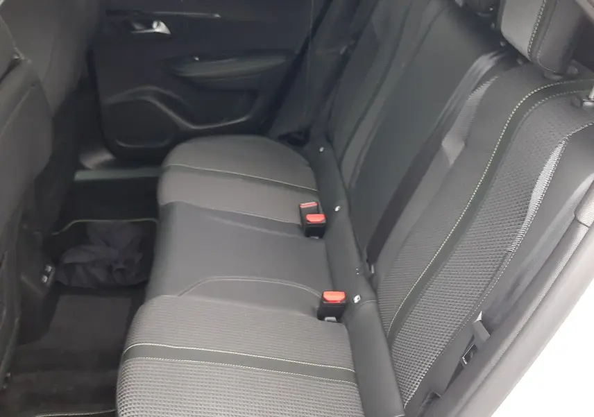 Vue intérieure côté droit des sièges arrière noirs avec surpiqûres vertes d'un Peugeot 2008 2023 blanc nacré.