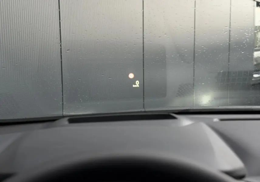 Vue intérieure du tableau de bord du Nissan Qashqai gris Squale 2025, affichage tête haute sur pare-brise avec pluie.