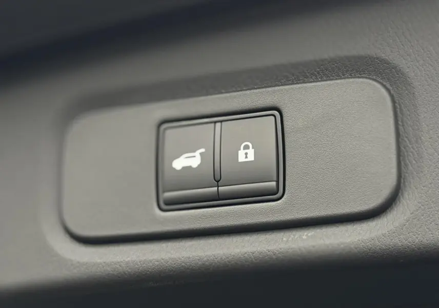 Gros plan sur les boutons d'ouverture électrique du hayon et de verrouillage dans l'habitacle du Nissan Qashqai gris Squale 2025.