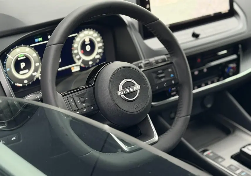 Vue intérieure rapprochée du volant noir et du tableau de bord numérique du Nissan Qashqai III e-Power gris Squale.