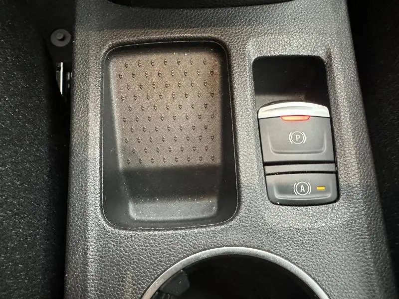Gros plan sur la console centrale noire du Renault Captur 2025, montrant les boutons de frein à main électronique et arrêt auto.