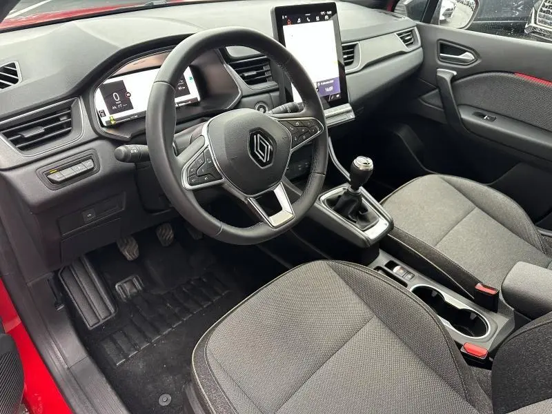 Vue intérieure côté conducteur du Renault Captur 2025 avec volant multifonction, boîte manuelle et sellerie grise.