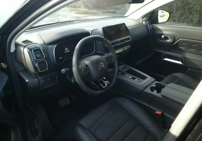 Vue intérieure côté conducteur du Citroën C5 Aircross 2024, avec tableau de bord noir et écran tactile central.