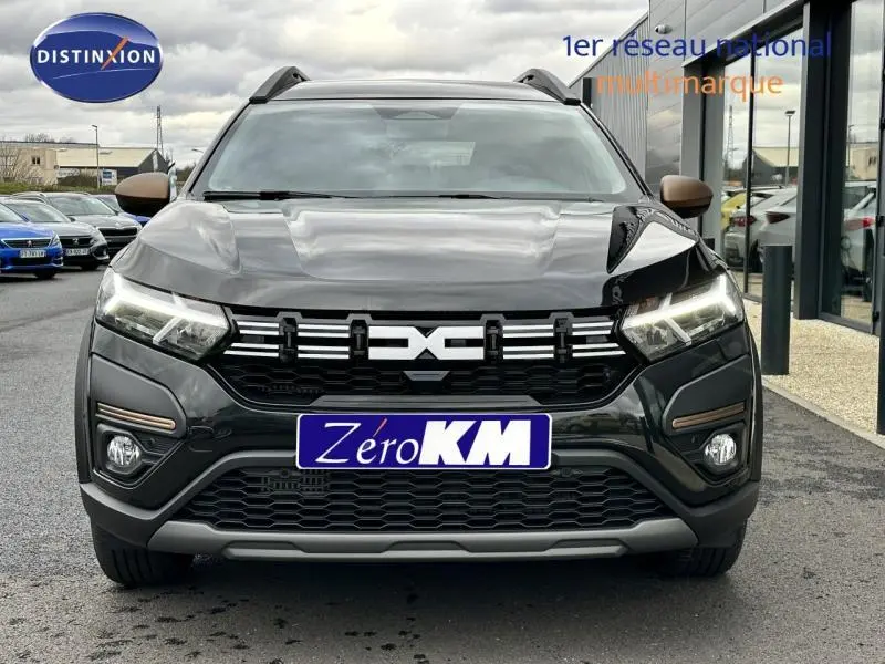 Vue frontale d'un Dacia Jogger 1.6 hybrid 140ch Extreme noir nacré métallisé avec calandre marquée et phares LED allumés.