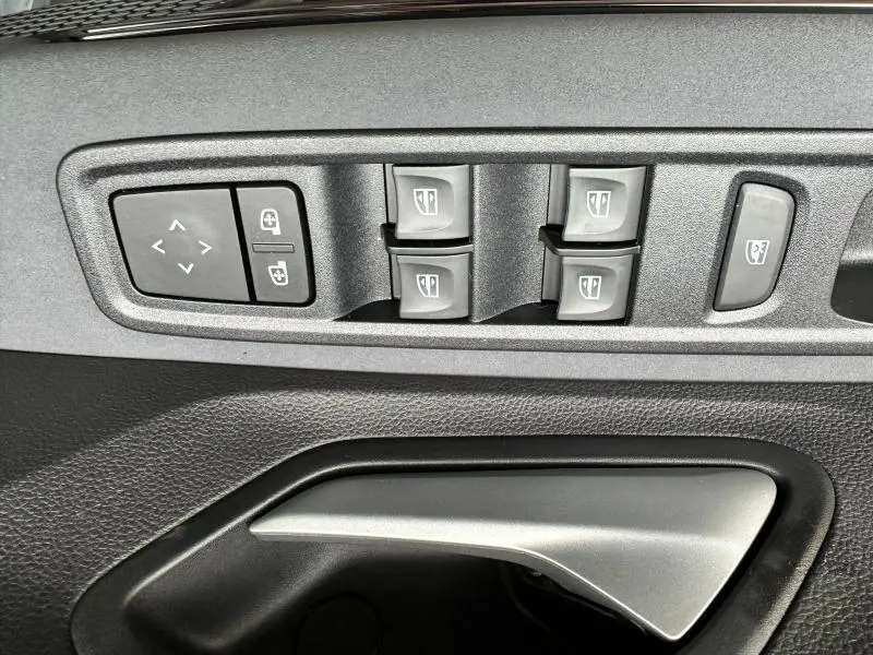 Gros plan sur les commandes des vitres électriques et rétroviseurs côté conducteur du Dacia Jogger noir nacré.