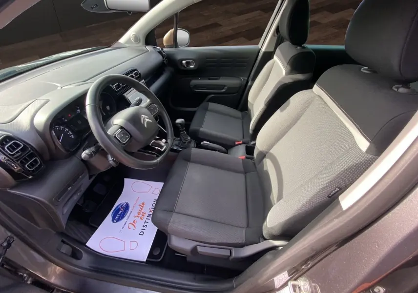 Vue intérieure côté conducteur de la Citroën C3 Aircross gris platinium, montrant les sièges tissu gris et le tableau de bord.