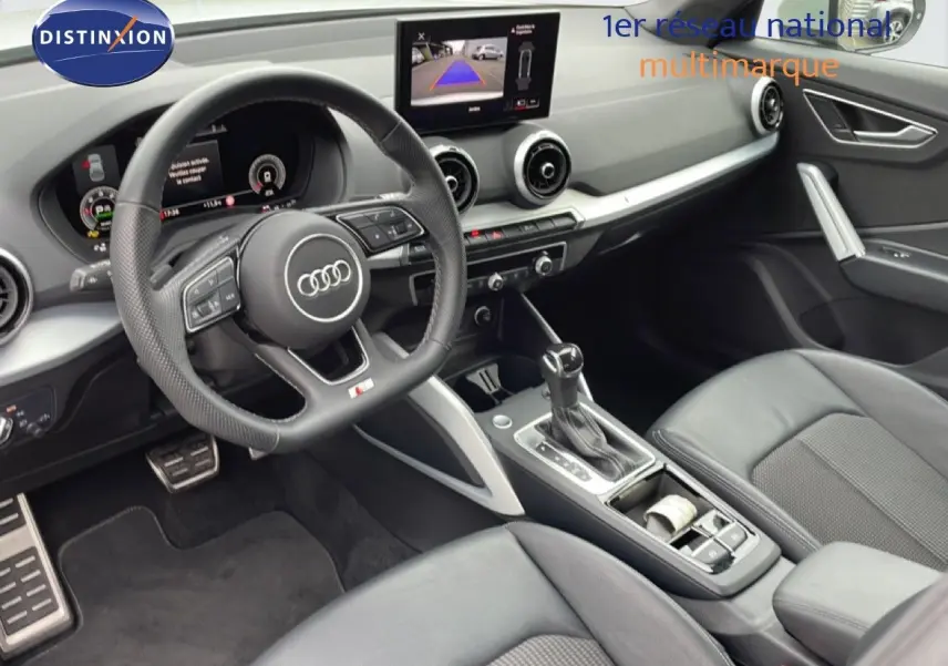 Vue intérieure côté conducteur de l'Audi Q2 35 2.0 TDI S-Line 2025 avec volant cuir perforé et écran multimédia central.