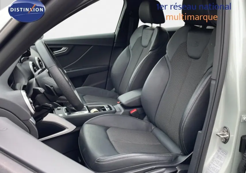 Vue intérieure côté conducteur de l'Audi Q2 argent rose métal, sièges sport cuir noir avec logo S-Line embossé.