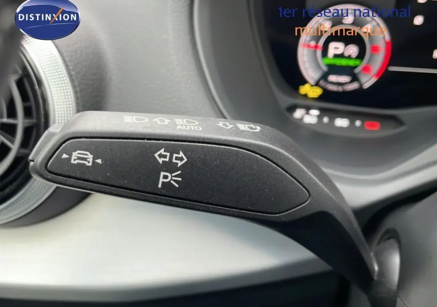 Gros plan sur la manette de clignotant noire avec symboles blancs dans l'habitacle d'un Audi Q2 35 2.0 TDI argent rose métal.