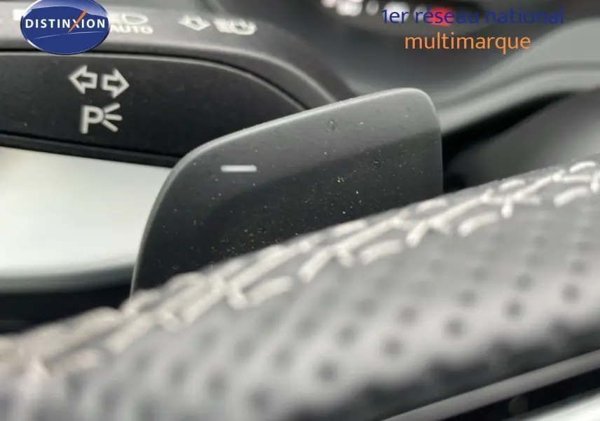 Gros plan sur la palette de changement de vitesse derrière le volant perforé de l'Audi Q2 argent rose métal.