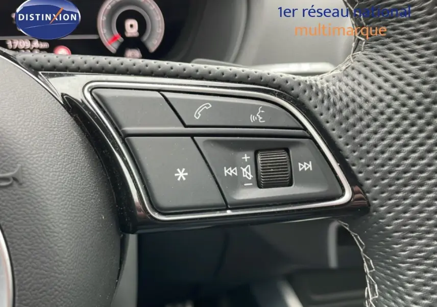 Gros plan sur les commandes multifonctions noires du volant perforé de l'Audi Q2 35 2.0 TDI S-Line 2025.