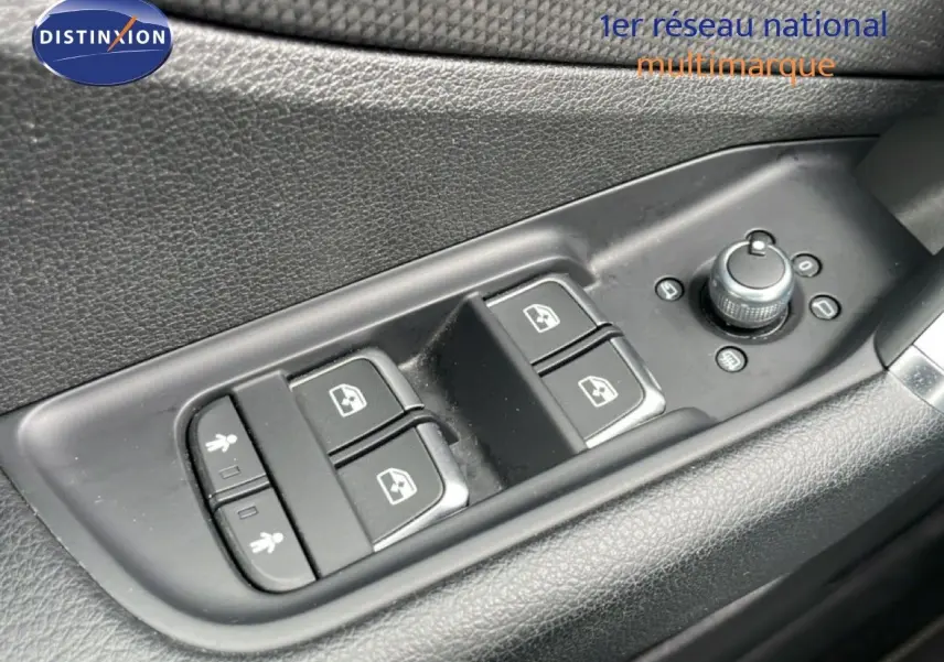 Gros plan sur les commandes de lève-vitres et réglage des rétroviseurs côté conducteur d’un Audi Q2 argent rose.