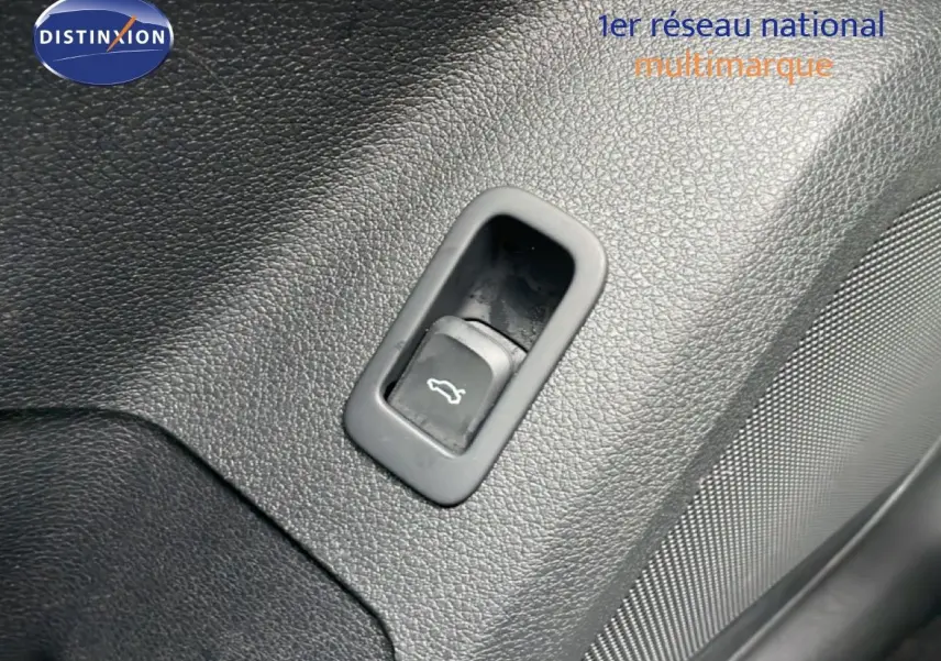 Gros plan sur le bouton d'ouverture du coffre intégré dans le revêtement noir texturé de l'Audi Q2.