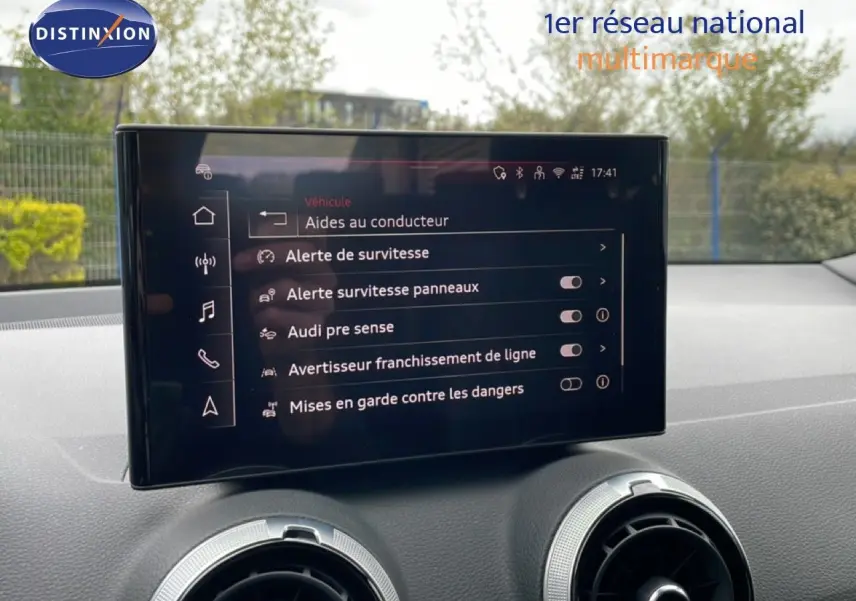 Écran central tactile affichant les aides à la conduite dans l’Audi Q2 argent rose, vue intérieure avant.