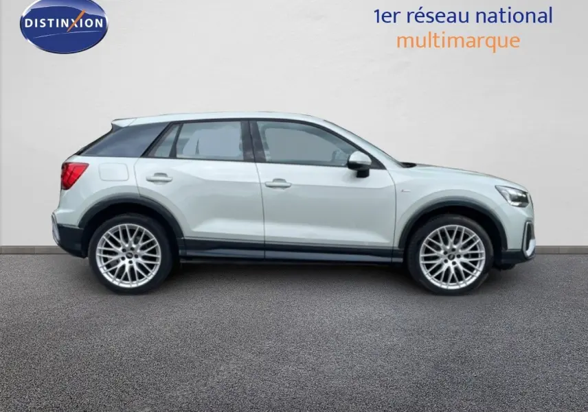 Audi Q2 argent rose métal en profil droit, avec jantes alliage et toit noir contrasté, sur fond neutre.