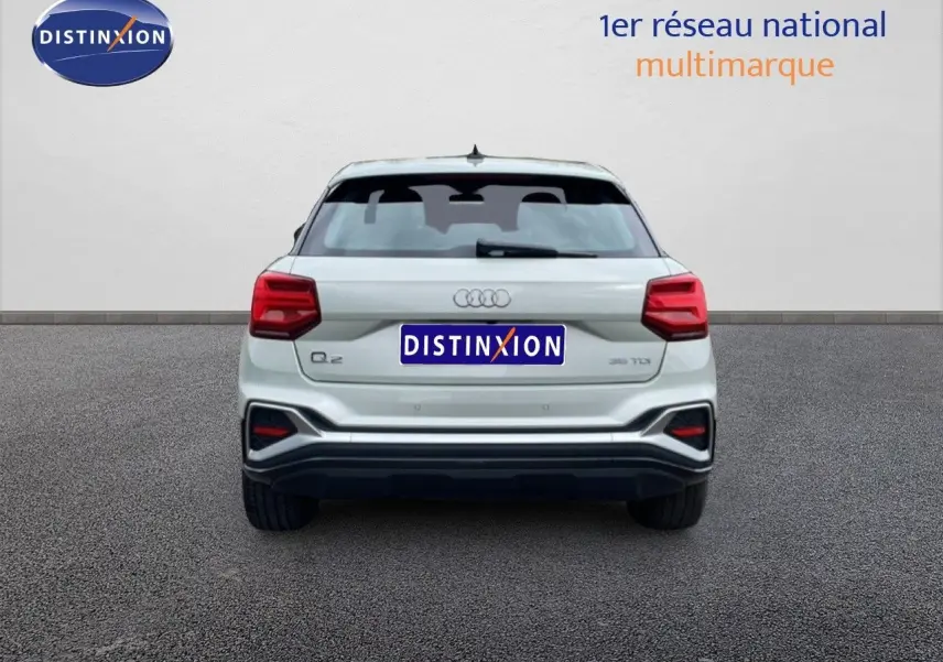 Vue arrière d'un Audi Q2 argent rose métal 2025 avec feux rouges et logo distinctif sur fond neutre.