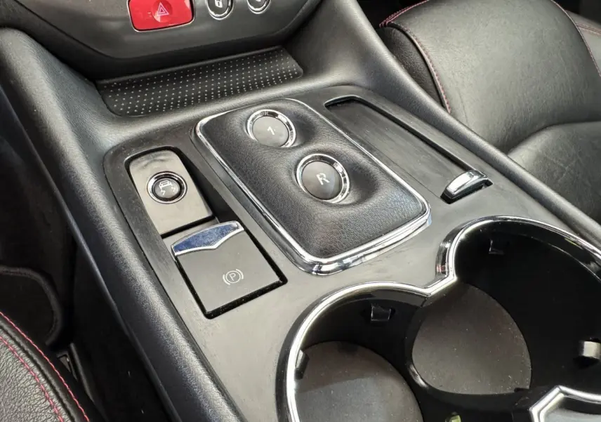Gros plan sur la console centrale noire de la Maserati Granturismo S 4.7 2010, avec boutons de boîte auto et porte-gobelets.