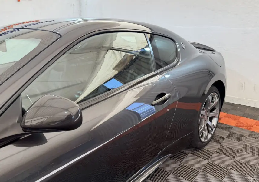 Vue latérale droite d'une Maserati Granturismo S 4.7 gris foncé avec rétroviseur en carbone et jantes sport.