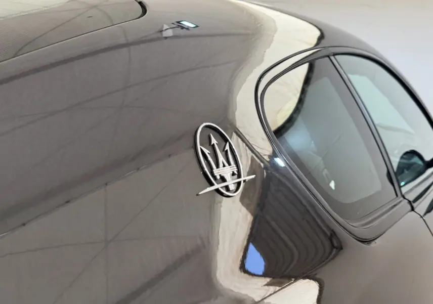 Vue rapprochée du côté gauche arrière d’une Maserati Granturismo S 4.7 gris foncé avec logo trident visible.