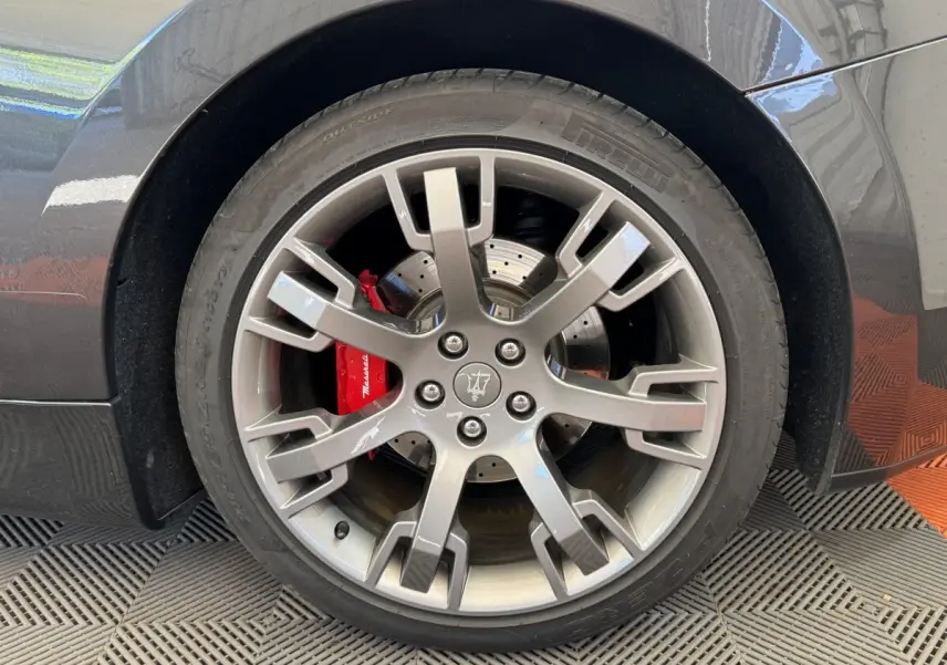 Gros plan sur la roue arrière droite gris foncé d'une Maserati Granturismo S 4.7 avec étrier de frein rouge marqué Maserati.