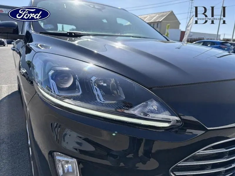 Gros plan sur le phare avant gauche du Ford Kuga noir Agate Métallisée 2023, mettant en valeur son design moderne.