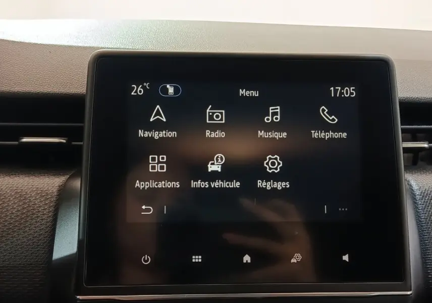 Écran tactile central de la Renault Clio Business E-TECH 140 blanc, affichant le menu principal avec navigation et radio.