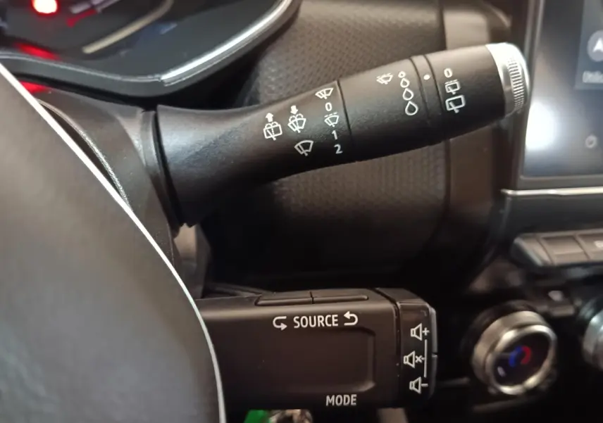 Gros plan sur les commandes au volant de la Renault Clio Business E-TECH 140 blanche, avec boutons source et essuie-glace.