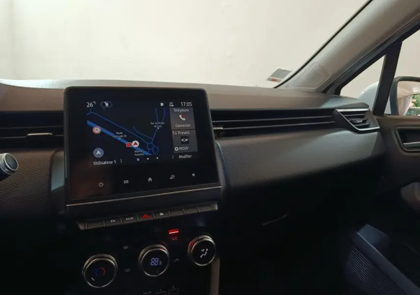 Vue intérieure du tableau de bord de la Renault Clio Business E-TECH 140 blanc, avec écran tactile de navigation allumé.