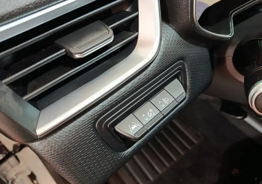 Gros plan sur les commandes d'assistance à la conduite et réglage des phares dans l'habitacle de la Renault Clio Business E-TECH 140 blanche.