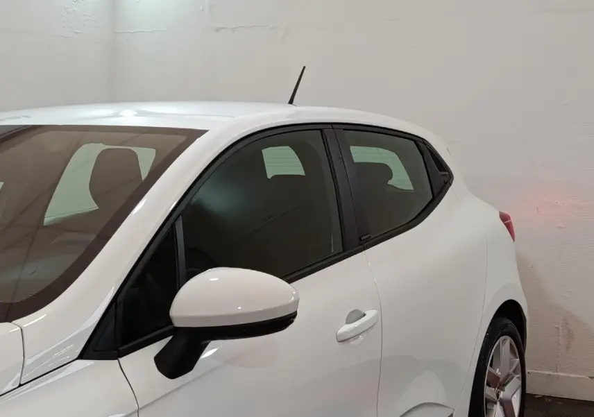 Vue de profil côté gauche d'une Renault Clio Business E-TECH blanche avec rétroviseur et poignée de porte visibles.