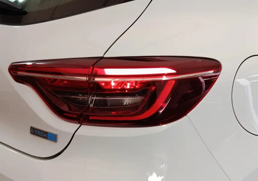 Gros plan sur le feu arrière droit rouge d’une Renault Clio Business E-TECH 140 blanche avec logo hybride.