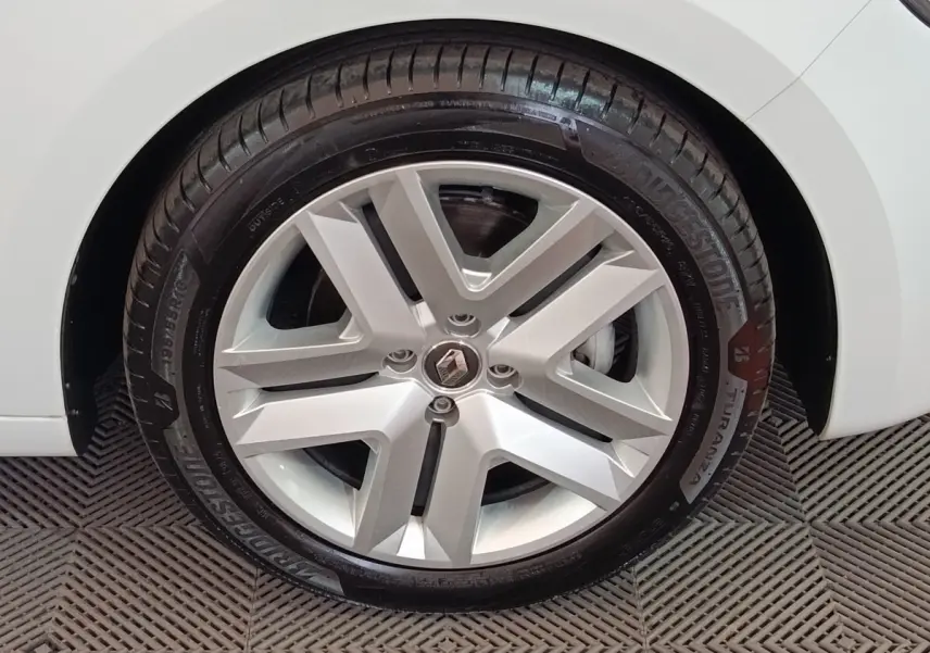 Gros plan sur la roue avant droite blanche d'une Renault Clio Business E-TECH 140 avec jante alliage et pneu Bridgestone.
