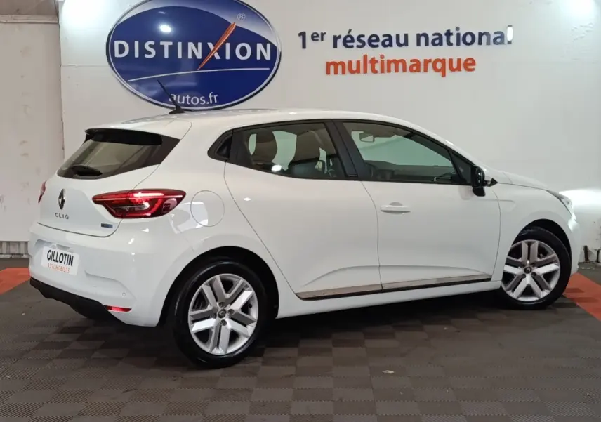 Renault Clio Business E-TECH blanc vue de profil droit en intérieur, avec jantes alliage et feux arrière LED allumés.