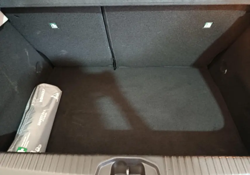 Coffre vide vu de dessus de la Renault Clio Business E-TECH 140 blanc, avec trousse de secours à gauche.