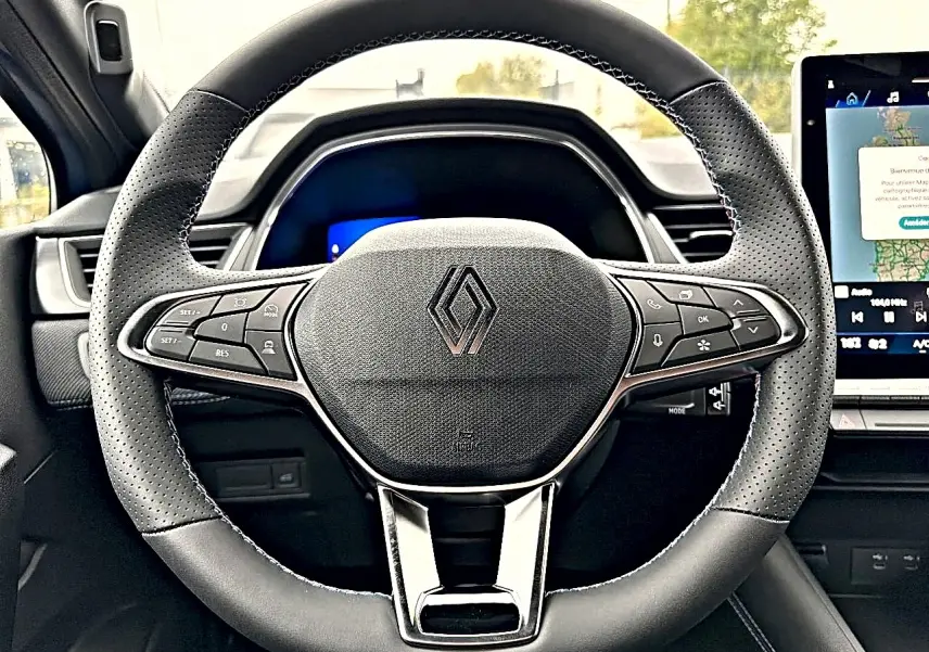 Vue rapprochée du volant multifonction noir de la Renault Symbioz 2026 avec logo central et écran tactile à droite.