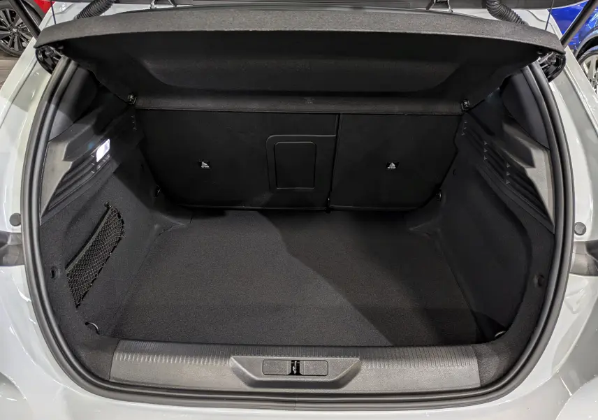 Coffre ouvert vu de l'arrière d'une Peugeot 308 GT blanche, montrant un espace de chargement propre et bien fini.