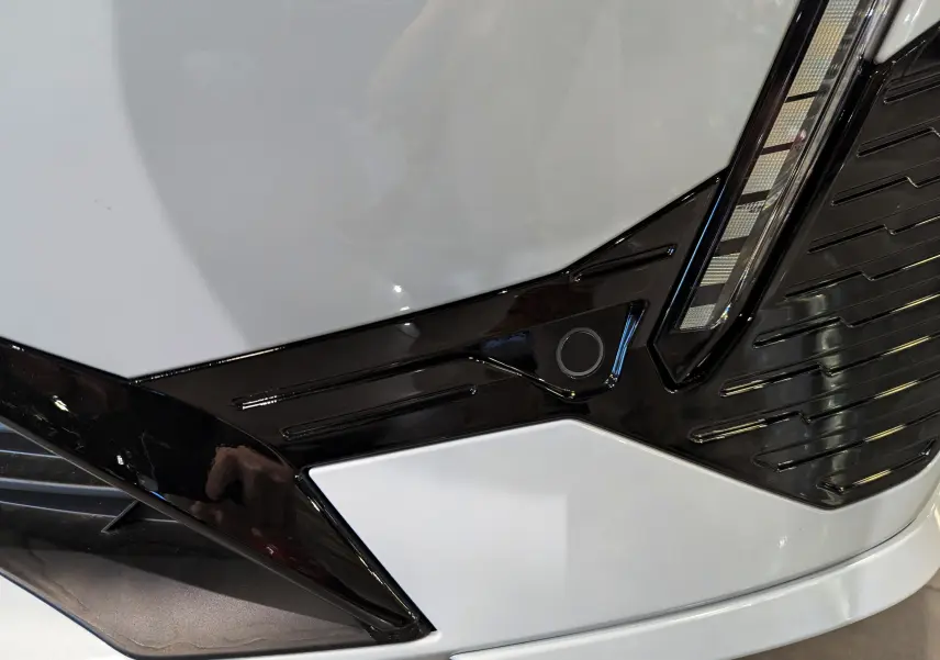 Détail du pare-chocs avant blanc Okénite du Peugeot 308 2024 avec insert noir brillant et capteur de stationnement.